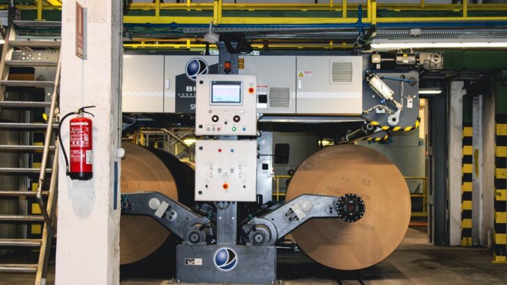 Heavy machinery processing industrial paper rolls at the Klingele corrugated cardboard manufacturing plant.